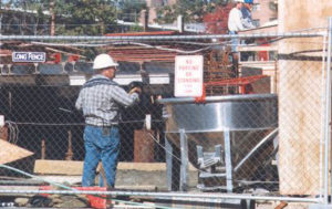 Construction Worker Standing Near Chain Link Temporary Fence