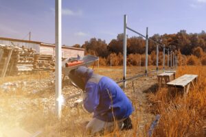 A man installs a fence with a welding torch.