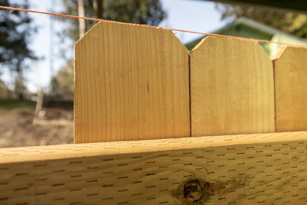 close up of the top of a wood fence with leveling chalk rope